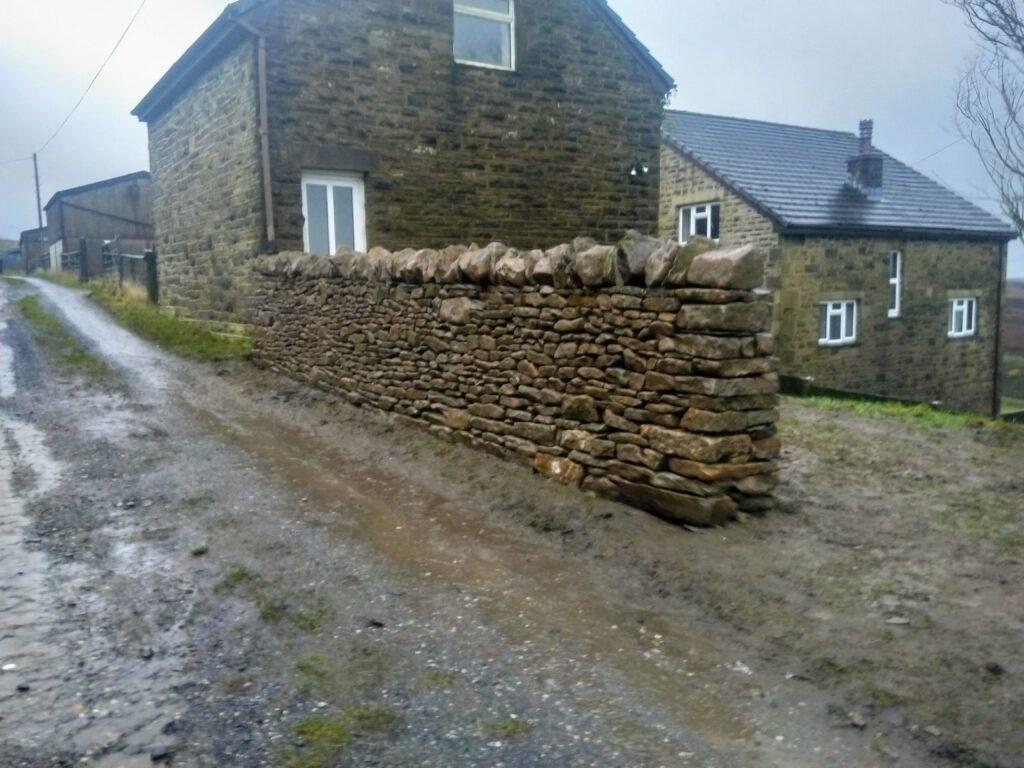dry stone wall repair near Bolton, Greater Manchester. On a farm up a hill.